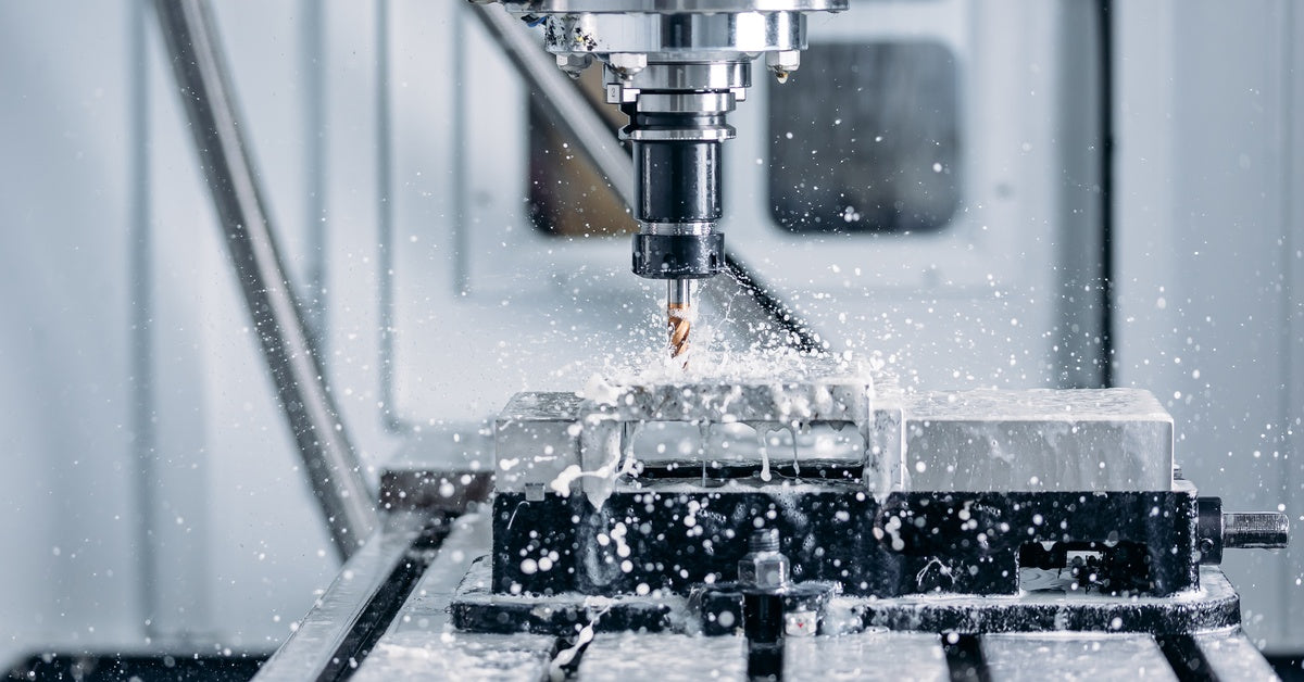 An automated CNC machine being used to cut through silver blocks of metal on a table in a fabrication shop.