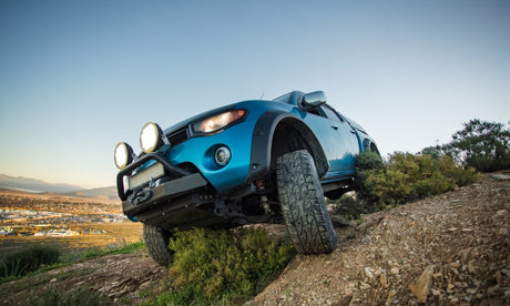 A welder is using a machine to join two pieces of metal. The worker is wearing a protective mask and gloves to avoid sparks.